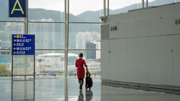 A flight attendant for Cathay Pacific Airways Ltd. at Hong Kong International Airport in Hong Kong, China, on Monday, Aug. 8, 2022. Hong Kong will reduce the period of time people entering the city must spend in hotel quarantine to three days from seven, a bolder-than-expected easing of its strict Covid-19 travel curbs, yet still leaving the Asian financial hub isolated in a world that’s mostly moved on from the pandemic.