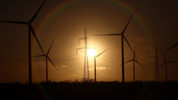 The sun sets beyond wind turbines and electricity power lines. Photographer: Chris Ratcliffe