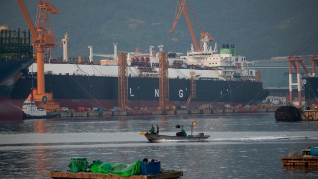 A fishing boat sails past liquefied natural gas (LNG) tankers under construction at the Daewoo Shipbuilding & Marine Engineering Co. shipyard in Geoje, South Korea, on Friday, June 5, 2020. Qatar has signed a deal worth around $20 billion with South Korean shipbuilders to help cement its position as the world’s largest producer of liquefied natural gas. Photographer: SeongJoon Cho/Bloomberg