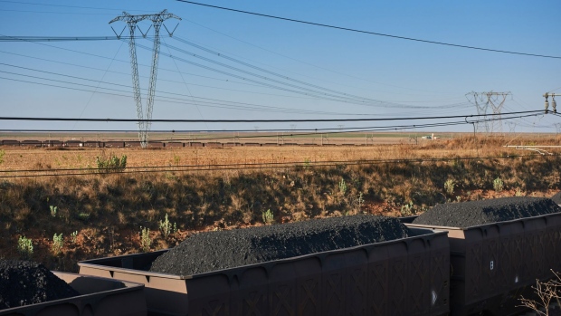 Freight wagons transport coal past electricity transmission towers, heading from the Mafube open-cast coal mine, operated by Exxaro Resources Ltd. and Thungela Resources Ltd., towards Richard's Bay coal terminal, in Mpumalanga, South Africa on Thursday, Sept. 29, 2022. South Africa relies on coal to generate more than 80% of its electricity, and has been subjected to intermittent outages since 2008 because state utility Eskom Holdings SOC Ltd. can't meet demand from its old and poorly maintained plants.