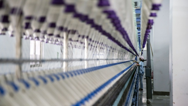 A worker stands in front of a machine on a yarn production line at the Fujian Strait Textile Technology Co. factory in Putian, Fujian province, China, on Monday, Feb. 8, 2021. China may have got its control of Covid down to a handful of new cases per day, but the restrictions, quarantines and travel curbs to keep it that way have forced millions of factory workers to give up the idea of a traditional family gathering. Photographer: Qilai Shen/Bloomberg