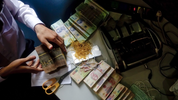 A customer at Joint-Stock Commercial Bank for Foreign Trade of Vietnam, or Vietcombank, counts dong bank notes prior to making a deposit in Hanoi, Vietnam, on Thursday, July 28, 2011.  Photographer: Justin Mott/Bloomberg 