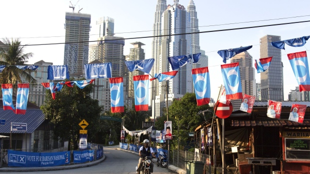 A motorcyclists rides past campaign flags and banners as the Petronas Twin Towers stand in the background in Kuala Lumpur, Malaysia, on Tuesday, May 8, 2018. Malaysia is holding a general election on May 9.