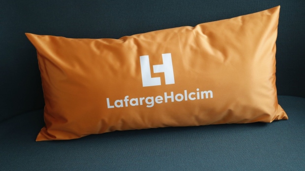 A logo sits on a cushion in the reception area at the LafargeHolcim Ltd. headquarters in Zug, Switzerland, on Tuesday, Sept. 3, 2019. After two painful years of restructuring, LafargeHolcim Chief Executive Officer Jan Jenisch says the world’s biggest maker of building materials is finally ready for acquisitions again -- as long as they don't threaten the progress he's made so far. Photographer: Stefan Wermuth/Bloomberg