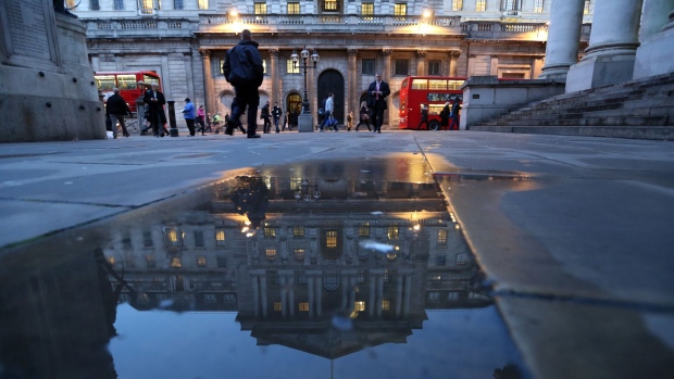 Lights illuminate windows inside the Bank of England as the central bank is reflected in a rain water puddle in London, U.K., on Wednesday, Jan. 8, 2014. The U.K. central bank's Monetary Policy Committee holds its first meeting of the year tomorrow and will keep its benchmark rate at a record-low 0.5 percent, according to a Bloomberg News survey of economists.