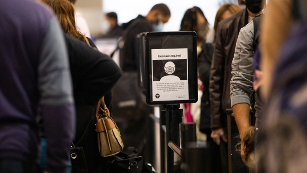 A sign requiring protective face masks for all travelers in the security line the Detroit Metropolitan Wayne County Airport in Romulus, Michigan, U.S., on Wednesday, Dec. 22, 2021. Airline passenger numbers in the U.S. totaled 1.98 million on Dec. 21, compared with 992,167 the same weekday a year earlier, according to the Transportation Security Administration. Photographer: Emily Elconin/Bloomberg