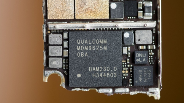 A Qualcomm Inc. baseband modem integrated circuit (IC) chip, bottom, of an Apple Inc. iPhone 6 smartphone is seen in an arranged photograph in Bangkok, Thailand, on Saturday, Feb. 3, 2018. Apple Chief Executive Officer Tim Cook told shareholders on Feb. 13 at the company's annual meeting to expect higher dividends and stressed that succession planning is a priority.