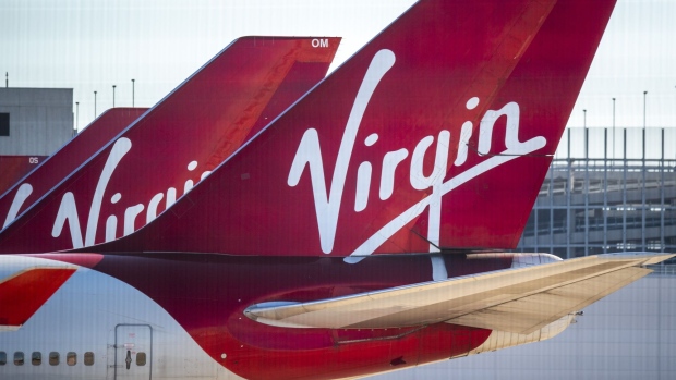 The Virgin logo sits on the tail-fins of passenger aircraft, operated by Virgin Atlantic Airways Ltd, grounded on the tarmac at Manchester Airport, operated by Manchester Airport Plc, in Manchester, U.K., on Monday, June 1, 2020. More than 200 U.K. travel and hospitality executives, including the head of London’s iconic Ritz hotel, joined a chorus of airlines and airports calling for the government to introduce air bridges to boost tourism and scrap contentious plans to quarantine visitors. Photographer: Anthony Devlin/Bloomberg