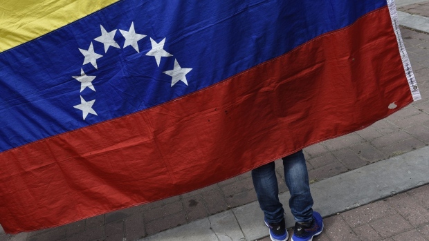An attendee holds a Venezuelan flag as Juan Guaido, president of the National Assembly who swore himself in as the leader of Venezuela, not pictured, speaks during a rally to propose amnesty laws for police and military, in the Las Mercedes neighborhood of Caracas, Venezuela, on Saturday, Jan. 26, 2019. Secretary of State Michael Pompeo took the U.S. effort to recognize Guaido as Venezuela's rightful leader to the United Nations, part of a broader campaign to replace President Nicolas Maduro, and said the choice is between freedom and mayhem.