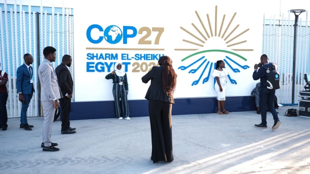 Attendees take photographs in front of a banner at the COP27 climate conference in Sharm El-Sheikh, Egypt.