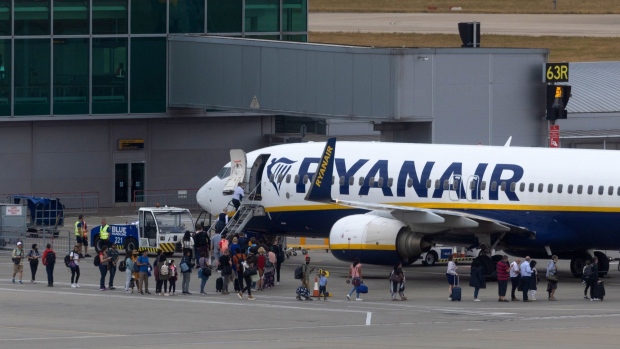 Passengers board an aircraft, operated by Ryanair Holdings Plc, on the tarmac at London Stansted Airport, operated by Manchester Airport Plc, in Stansted, U.K., on Monday, July 25, 2022. Ryanair said passengers remain cautious about booking, clouding its prospects beyond a summer travel boom in which it’s suffering less disruption than many of its rivals. Photographer: Chris Ratcliffe/Bloomberg