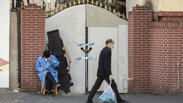 A worker in protective gear guards an entrance to a neighborhood placed under lockdown due to Covid-19 in Shanghai, China, on Monday, Nov. 7, 2022. China’s daily Covid cases jumped to the highest in more than six months, as outbreaks flared across the nation and health officials declared the nation will stick with its strict virus controls. Photographer: Qilai Shen/Bloomberg