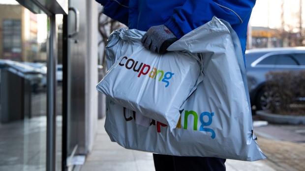 A Coupang Corp. employee holds packages in front of an apartment building in Bucheon, South Korea, on Friday, Feb. 19, 2021. South Korean e-commerce giant Coupang filed for an initial public offering in the U.S. and that could raise billions of dollars to battle rivals and kick off a record year for IPOs in the Asian country.