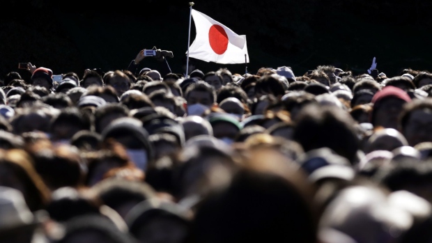 A Japanese flag flies as members of the public attend the New Year's appearance by the Japanese royal family at the Imperial Palace in Tokyo, Japan, on Wednesday, Jan. 2, 2019. Japan's Emperor Akihito, the head of the world oldest hereditary monarchy, is scheduled to abdicate on April 30, handing over the position to his son, Crown Prince Naruhito.