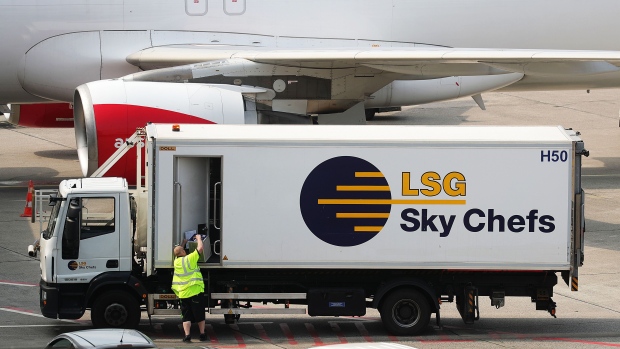 A worker unloads a crate from a LSG Sky Chefs catering truck, a unit of Deutsche Lufthansa AG, beside an Austrian Airlines jet at Tegel airport in Berlin, Germany, on Monday, July 29, 2019. Deutsche Lufthansa AG is considering a shift to a corporate holding structure, seeking to streamline Europe's biggest airline group as it fights for market share. Photographer: Krisztian Bocsi/Bloomberg