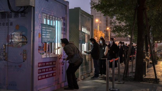 BEIJING, CHINA - NOVEMBER 09: An epidemic control worker gives a man a nucleic acid test to detect COVID-19 as others wait in line at a public testing booth in the street on November 9, 2022 in Beijing, China. China has continued to stick to its strict zero tolerance COVID policy with mandatory testings, quarantines and lockdowns in an effort to control the spread of the virus. (Photo by Kevin Frayer/Getty Images)