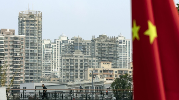A Chinese flag in front of residential buildings in Shanghai, China, on Monday, Oct. 17, 2022. Chinese President Xi Jinping signaled no change in direction for two main risk factors dragging down China’s economy -- strict Covid rules and housing market policies -- providing little lift to a worsening growth outlook. Photographer: Qilai Shen/Bloomberg