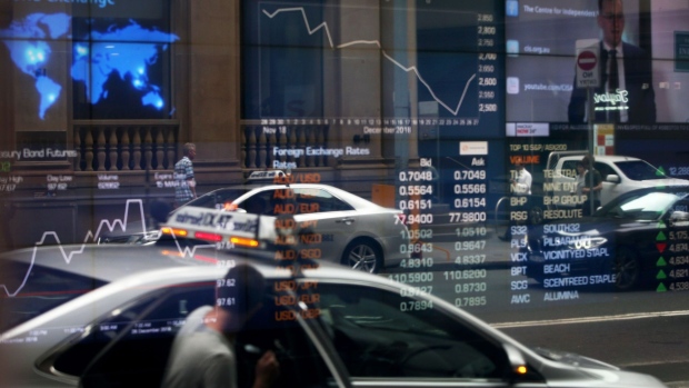 Vehicles are reflected in a window as electronic boards display stock information at the Australian Securities Exchange, operated by ASX Ltd., in Sydney, Australia, on Friday, Jan. 11, 2019. Australian consumer confidence slumped the most in more than three years, amid pessimism over falling property prices and economic growth, after the nation's dollar tumbled to the weakest in almost 10 years at the beginning of the month. Photographer: Lisa Maree Williams/Bloomberg