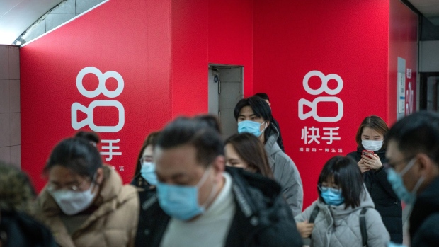 Passengers wearing protective masks walks past Kuaishou Technology advertisements at a subway station in Beijing, China, on Wednesday, Feb. 3, 2021. Kuaishou Technology, the operator of China's most popular video service after ByteDance Ltd.'s Douyin, raised HK$42 billion ($5.4 billion) after pricing its Hong Kong initial public offering at the top of a marketed range. Photographer: Yan Cong/Bloomberg