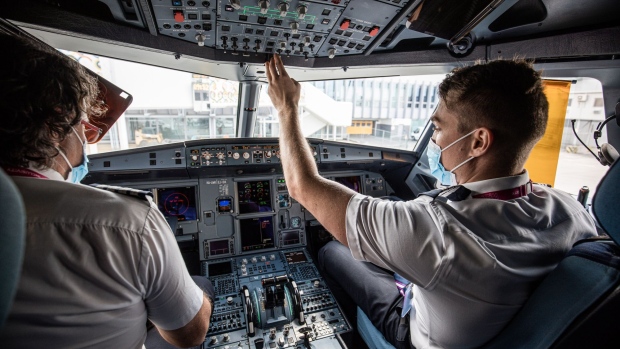 A pilot, left, and first officer wear protective face masks as they run through pre-flight checks in the cockpit on-board a passenger aircraft operated by Wizz Air Holdings Plc at Liszt Ferenc airport in Budapest, Hungary, on Monday, May 25, 2020. Wizz Air is plotting a major expansion at London Gatwick airport as rival carriers pull back, paving the way for the Hungarian low-cost carrier to emerge from the travel downturn with a bigger presence in the world’s busiest city for passenger traffic. Photographer: Akos Stiller/Bloomberg