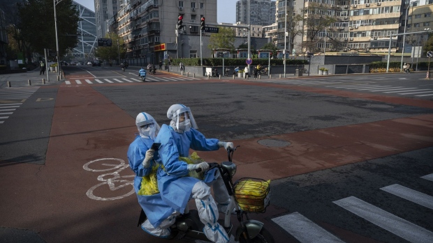 Epidemic control workers in a nearly empty street in Beijing on Nov. 23. Photographer: Kevin Frayer/Getty Images