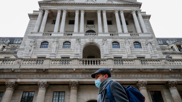 A pedestrian wearing a face mask walks past the Bank of England (BOE) in the City of London, U.K., on Thursday, March 18, 2021. The Bank of England is likely to emphasize its high bar for tightening monetary policy, a move to tamp down speculation that a quick recovery will force policy makers to push U.K. borrowing costs higher.