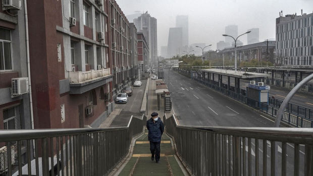 BEIJING, CHINA - NOVEMBER 24: A man wears a mask to prevent the spread of COVID-19 as he walks alone up an overpass next to a nearly empty street near the Central Business District on November 24, 2022 in Beijing, China. China recorded its highest number of COVID-19 cases since the pandemic began Wednesday, as authorities stuck to their strict zero tolerance approach to containing the virus with lockdowns, mandatory testing, mask mandates, and quarantines as it struggles to contain outbreaks. In an effort to try to bring rising cases under control, the government last week closed most stores and restaurants for inside dining, switched schools to online studies, and asked people to work from home. (Photo by Kevin Frayer/Getty Images)