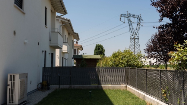 An electricity transmission tower and power lines near a residential area in Brescia, Italy, on Sunday, July 3, 2022. Italy's government plans further measures to cushion the impact of high energy prices, including extending a fuel tax holiday to the beginning of October, Il Messaggero newspaper reported.