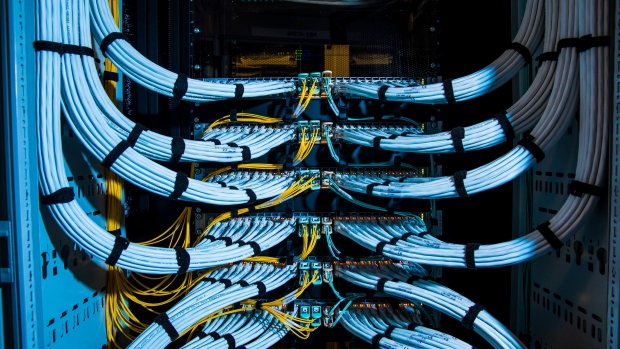 Fiber optic cables, center, and copper Ethernet cables feed into switches inside a communications room at an office in London, U.K., on Monday, May 21, 2018. The Department of Culture, Media and Sport will work with the Home Office to publish a white paper later this year setting out legislation, according to a statement, which will also seek to force tech giants to reveal how they target abusive and illegal online material posted by users. Photographer: Jason Alden/Bloomberg