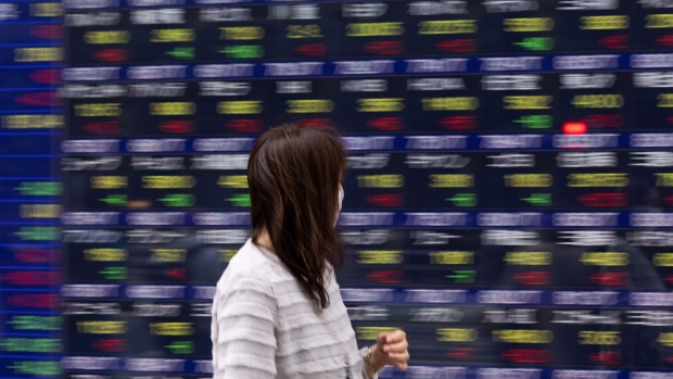 A pedestrian passes an electronic stock board outside a securities firm in Tokyo, Japan, on Monday, Nov. 21, 2022. The world's central banks must keep raising interest rates to fight soaring and pervasive inflation, even as the global economy sinks into a significant slowdown, the OECD said. Photographer: SeongJoon Cho/Bloomberg