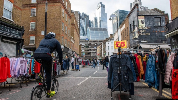 A cyclist passes empty clothing stalls at Petticoat Lane Market with the City of London skyline behind in London, UK, on Friday, Nov. 11, 2022. The UK economy shrank in the third quarter for the first time since the final lockdown of the pandemic as the cost of living crisis squeezed spending and the extra bank holiday for the Queen’s funeral shut businesses. Photographer: Chris J. Ratcliffe/Bloomberg