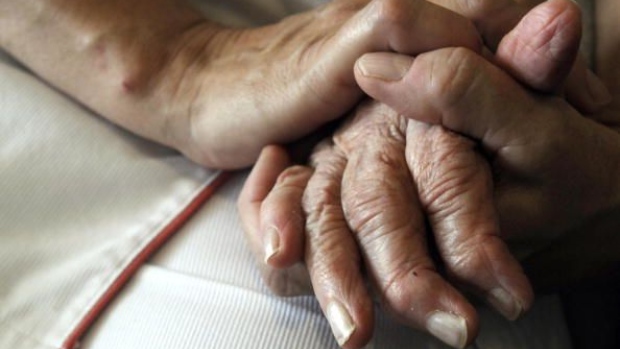 A nurse holds the hands of a person suffering from Alzheimer's disease. Photographer: Sebastien Bozon/AFP/Getty Images