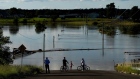 People look out at floodwaters from a closed road in the suburb of Pitt Town Bottoms in Sydney, Australia, on Wednesday, March 24, 2021. The one-in-100 year flooding event in recent days is causing supply disruptions in Australia. Photographer: Brent Lewin/Bloomberg