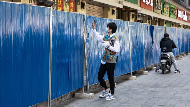 WUHAN, CHINA - NOVEMBER: (CHINA OUT) A resident wears a mask while uses phone scan the code to pay in front of makeshift barricade wall built to control entry and exit to a residential compound on November 2,2022 in Wuhan, Hubei Province, China.(Photo by Getty Images)