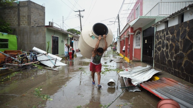 A resident carries a water catchment tank past debris after Hurricane Grace made landfall in Tecolitla, Veracruz state, Mexico, on Saturday, Aug. 21, 2021. Photographer: Hector Adolfo Quintanar Perez/Bloomberg