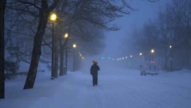 A resident carries a shovel down a street during a blizzard in Boston, Massachusetts, U.S., on Saturday, Jan. 29, 2022. A powerful winter storm is whipping the U.S. Northeast with high winds, crashing surf, and quickly piling up snow on the country's major transportation routes, while canceling flights and leaving thousands without power.