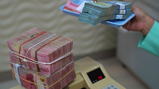 A bundles of Indonesian 50,000 rupiah banknotes on a tray next to a bundle of Indonesian 100,000 rupiah banknotes on a money counting machine at a currency exchange office in Jakarta, Indonesia, on Wednesday, March 2, 2022. The dollar is rising against virtually every peer as fallout from the sanctions levied against Russia supercharge demand for the world’s reserve currency. Photographer: Dimas Ardian/Bloomberg