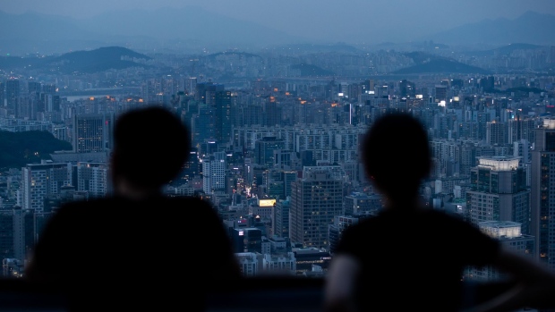 People are silhouetted as they look at a city skyline from an observation deck of Woomyeon mountain at dusk in Seoul, South Korea, on Thursday, July 9, 2020. South Korea’s government is preparing new regulations to curb excessive house price gains that have fueled public discontent over inequality and property speculation. Photographer: SeongJoon Cho/Bloomberg
