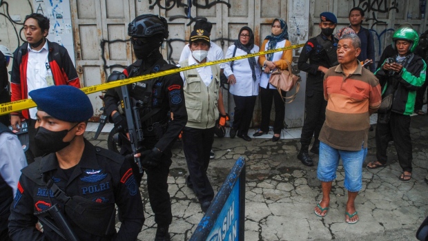 Bystanders look on as police secure the site of a suicide bombing outside a police station at Astanaanyar in Bandung, West Java province, on December 7 Photographer: Timur Matahari/AFP/Getty Images