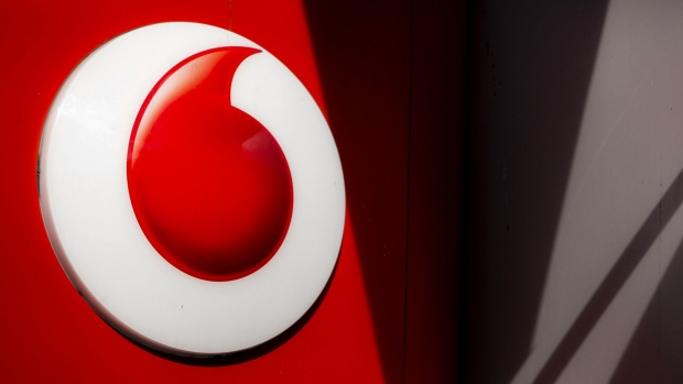 A logo sits on a sign outside a Vodafone store, operated by Vodafone Group Plc in London, U.K., on Monday, Sept. 2, 2013.  Photographer: Jason Alden/Bloomberg