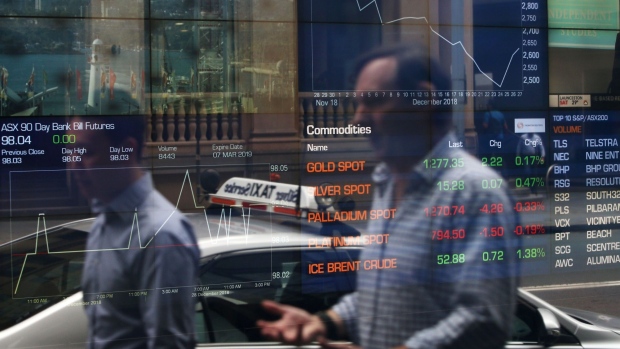 Pedestrians are reflected in a window as electronic boards display stock information at the Australian Securities Exchange, operated by ASX Ltd., in Sydney, Australia, on Friday, Jan. 11, 2019. Australian consumer confidence slumped the most in more than three years, amid pessimism over falling property prices and economic growth, after the nation's dollar tumbled to the weakest in almost 10 years at the beginning of the month. Photographer: Lisa Maree Williams/Bloomberg