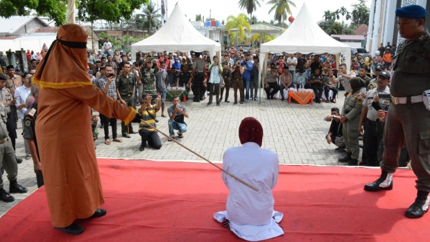 An Indonesian woman is whipped in public on charges of engaging in sexual relations, in Aceh Timur, in December 2019.  Photographer: Cek Mad/AFP/Getty Images