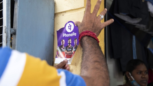 A PhonePe employee places an advertisement for the company's digital payment system outside a grocery store in Bengaluru, India, on Tuesday, Sept. 28, 2021. As online payments and digital loans in the second-most populous country soar at some of the fastest rates worldwide, money is pouring into India’s financial technology sector at an unprecedented pace. Photographer: Samyukta Lakshmi/Bloomberg