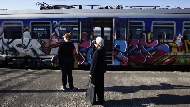 Commuters wait for a train as graffiti-covered railway carriages are seen alongside a platform at the central station in Zagreb, Croatia.