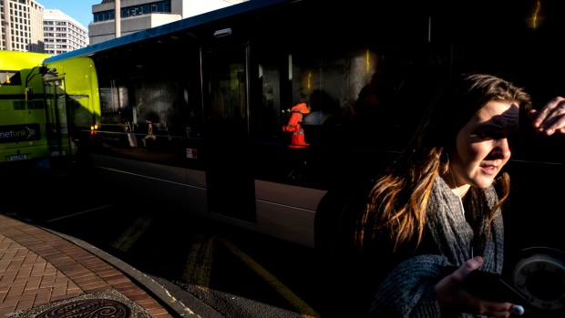 A woman waits at a bus stop in Wellington, New Zealand, on Wednesday, July 18, 2018. New Zealand inflation picked up in the second quarter amid higher fuel and construction costs while the impact from a weaker currency was less than expected. Photographer: Birgit Krippner/Bloomberg