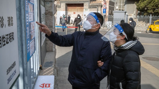 People wearing face shields read instructions on Covid rapid antigen tests outside a hospital in Beijing, China, on Wednesday, Dec. 14, 2022. Covid infections are surging in Beijing, disrupting official government work and keeping people at home after authorities made an about-turn in their policy of keeping virus cases under control.