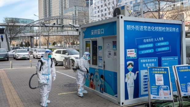 Workers wearing protective gear outside a Covid testing booth in Beijing, China, on Thursday, Dec. 15, 2022. China's economic activity worsened in November before the government abruptly dropped its Covid Zero policy, with more disruption to growth likely as infections surge.