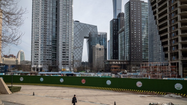 A pedestrian passes buildings in Beijing, China, on Thursday, Dec. 15, 2022. China's economic activity worsened in November before the government abruptly dropped its Covid Zero policy, with more disruption to growth likely as infections surge.