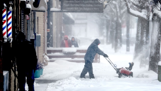 A worker clears snow from the front of a business in Chicago in Feb. 2022. 