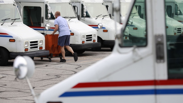 A United States Postal Service (USPS) employee loads a mail delivery vehicle at a post office in Louisville, Kentucky, US, on Wednesday, July 6, 2022. Beginning July 10, the cost of postage stamps will increase from 58 cents to 60 cents, and the cost to mail one metered mail piece will increase from 53 cents to 57 cents.